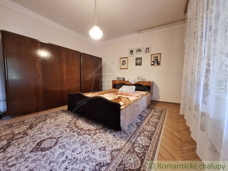 A bedroom in a family house with a wood-patterned floor, a large wardrobe, and curtains.