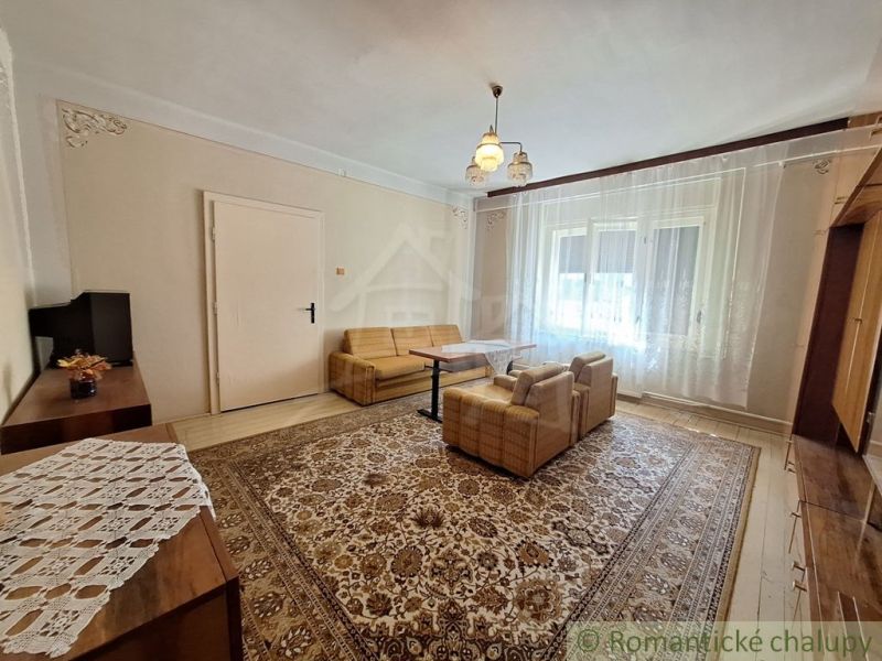 Living room in a family house with a carpet, sofa, and wooden decor flooring.