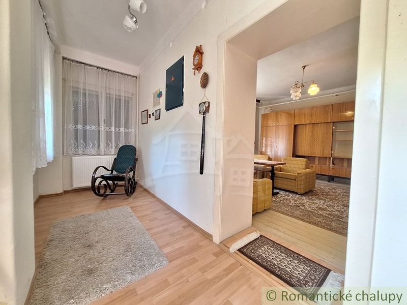 Interior of a family house with a wooden decor floor, rocking chair, and curtains.