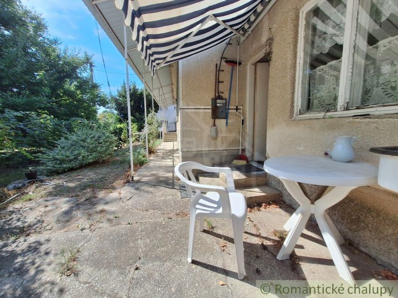 A family house in Moča with garden furniture, an awning, and windows with lace curtains.