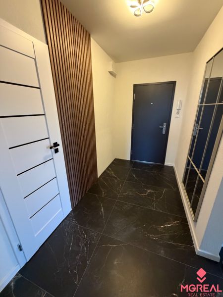 Entrance hallway with large tiles in a 3-room apartment, wooden decor on the wall.