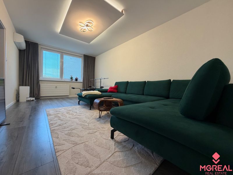 Living room in a three-room apartment with a wooden decor floor and a comfortable sofa.