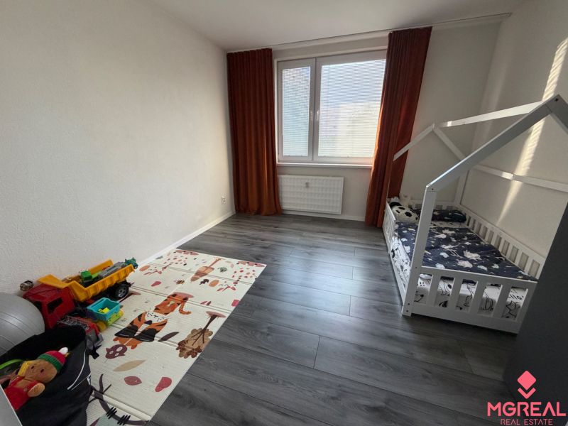 A children's room in a 3-room apartment with a wooden decor floor and a bed.