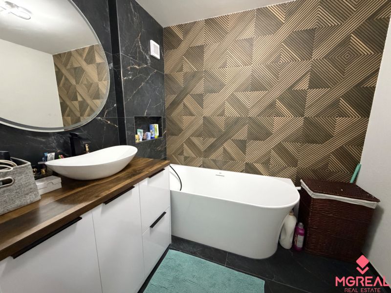 A bathroom in a 3-room apartment with a bold pattern on the wall and a freestanding bathtub.