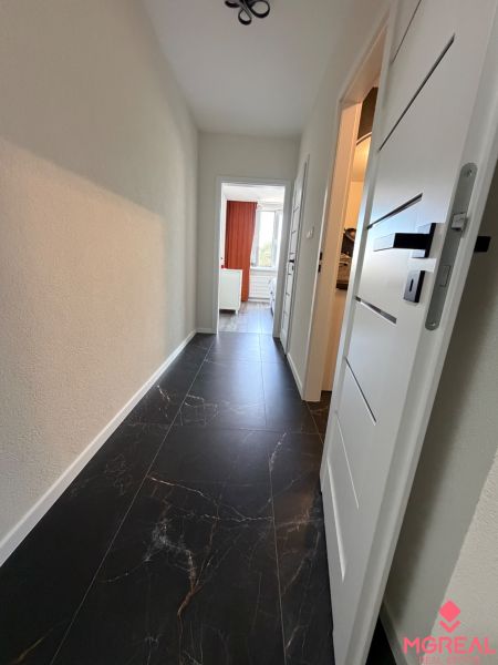 A hallway with dark tiles and white doors in a 3-room apartment.
