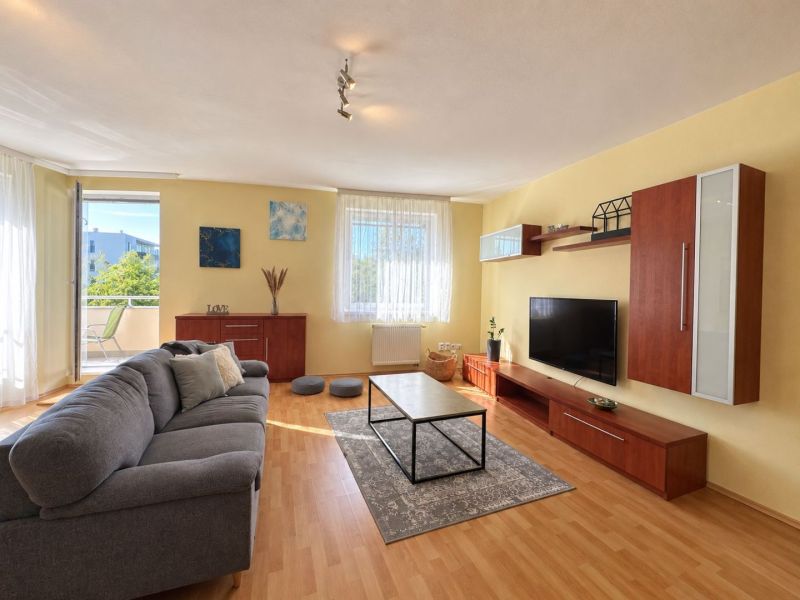 Living room with a sofa and a television in a 3-room apartment, floor with wooden decor.