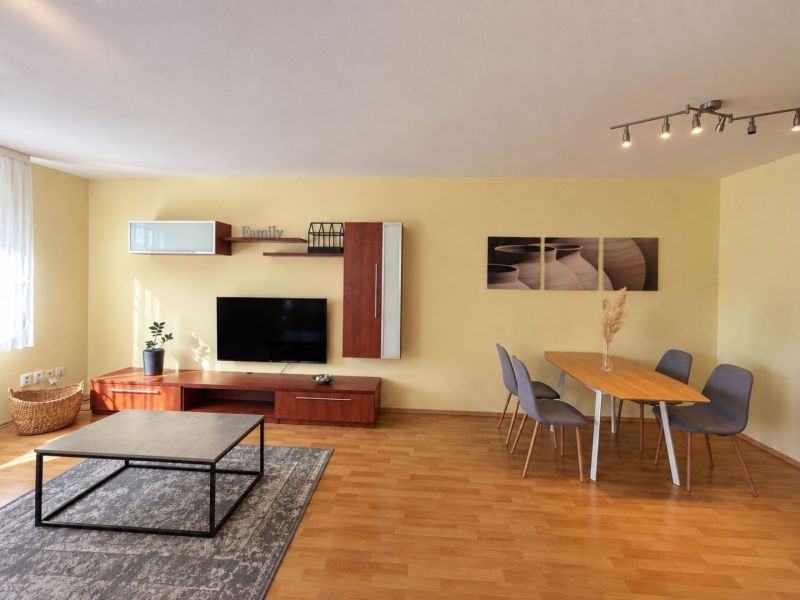 Living room in a 3-room apartment with a wooden decor floor and a dining table.
