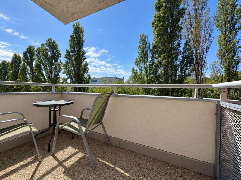 Balcony of a 3-room apartment in Bratislava - Ružinov with a view of trees, table and chairs.