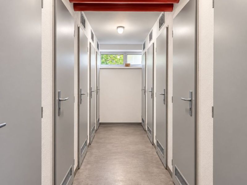 A corridor with multiple doors in a 3-room apartment, light walls and a gray floor.