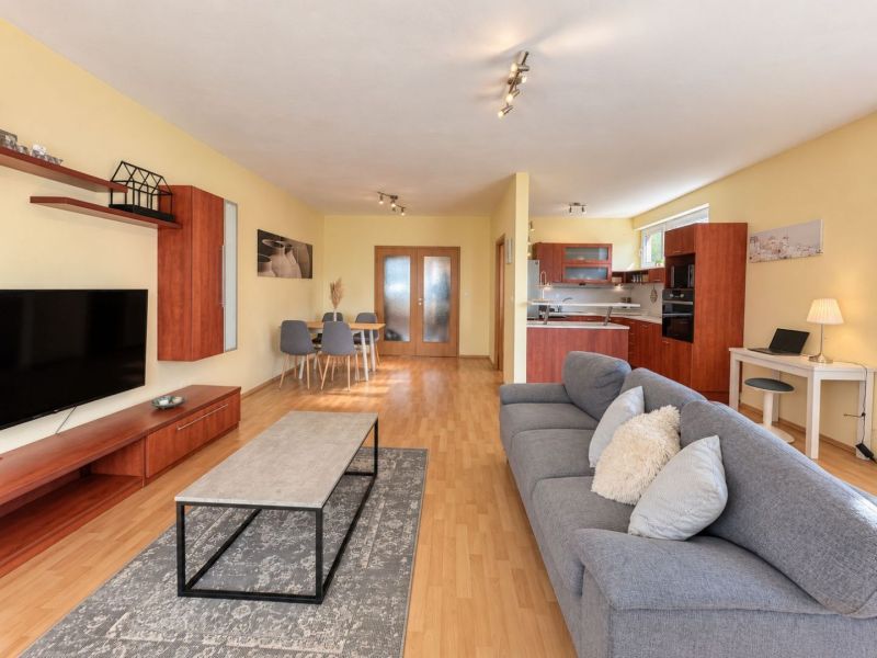 Living room in a 3-room apartment with a wooden decor floor, TV, and sofa.