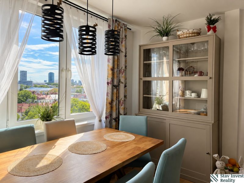 Dining area with a wooden table and a view in a 3-room apartment with plants.