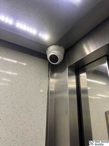Security camera in the corner of the elevator with lighting and metal cladding.
