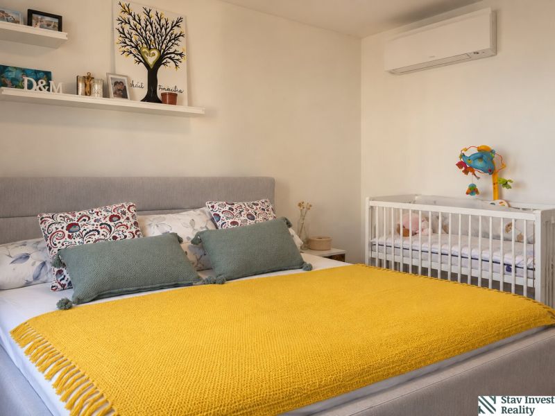 Bedroom in a 3-room apartment with a large bed, a baby crib, and decorations.