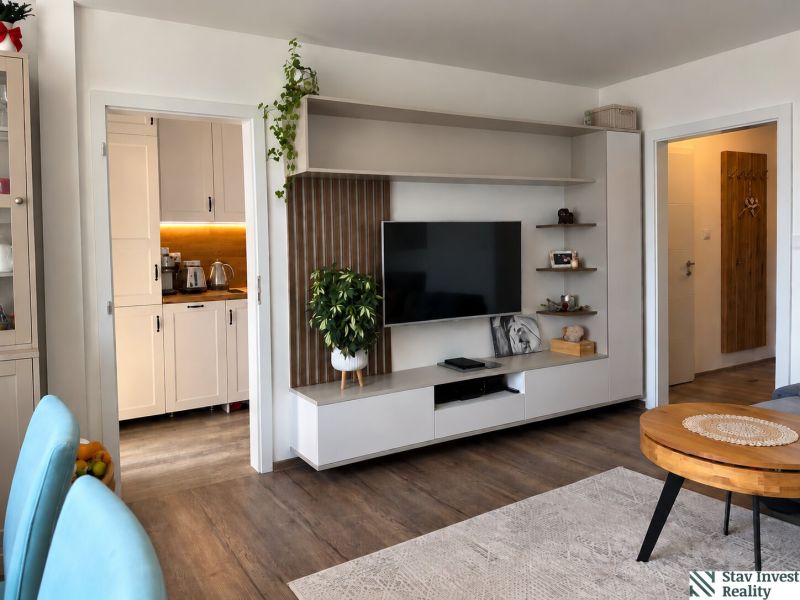 Living room with a TV wall and wooden decor flooring in a three-room apartment.