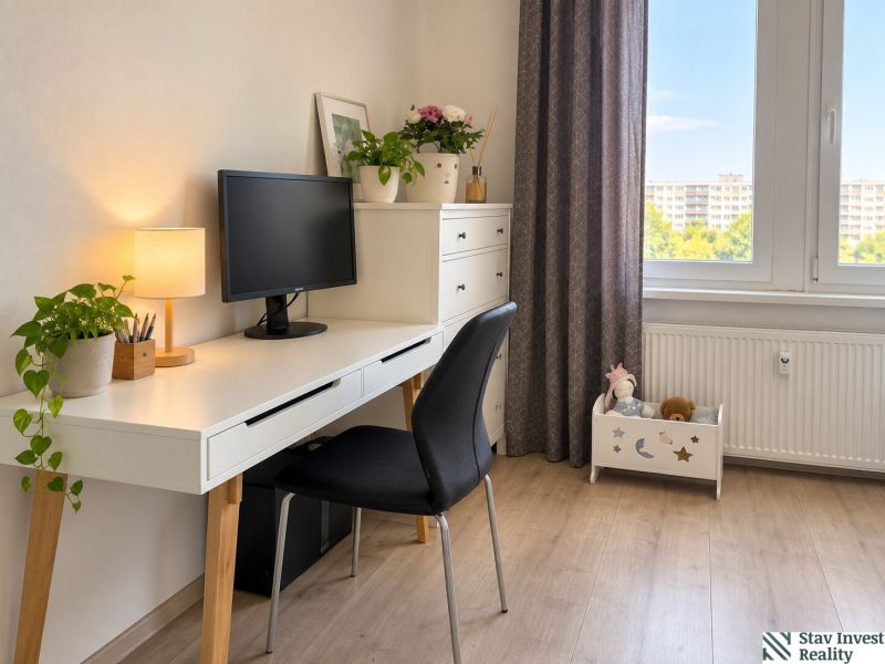 A workspace in a 3-room apartment with a desk, computer, and flowers on a floor with a wooden decor.