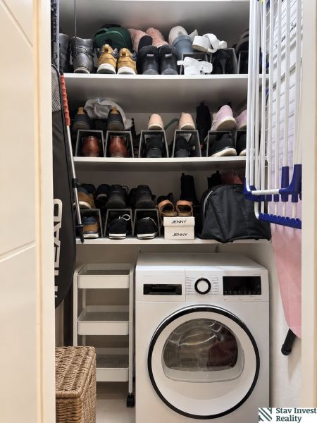 Storage space with shelves for shoes and a washing machine in a 3-room apartment.