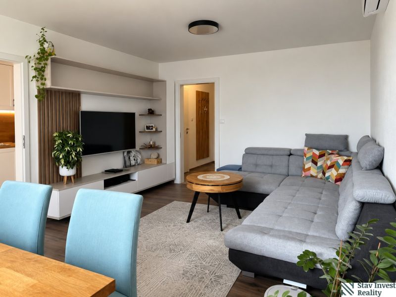 Living room in a 3-room apartment with a comfortable sofa, television, and plants.