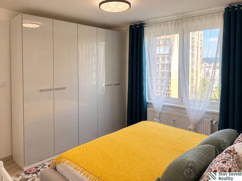 Bedroom in a 3-room apartment with a large wardrobe, yellow blanket, and a view from the window.