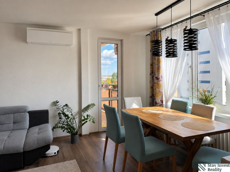 Dining room of a 3-room apartment with a wooden decor floor and a balcony.