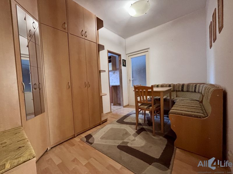 A hallway in a 2-room apartment with built-in wardrobes and a corner seating bench.