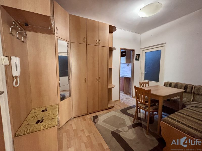 In the 2-room apartment, there is a wardrobe, a table, and a sofa, with a wooden decor floor.