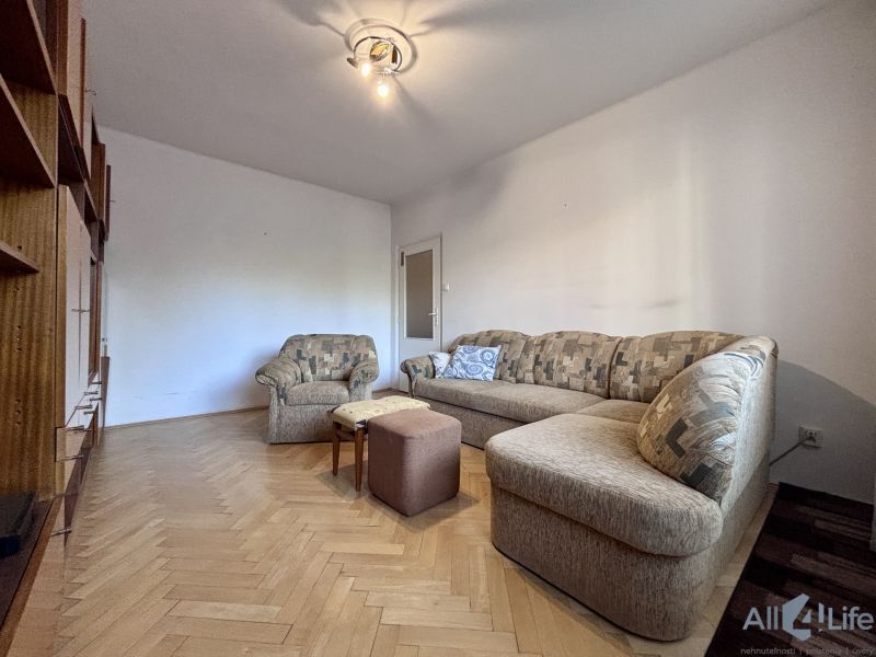 Living room with a sofa, an armchair, and a wooden decor floor in a two-room apartment.