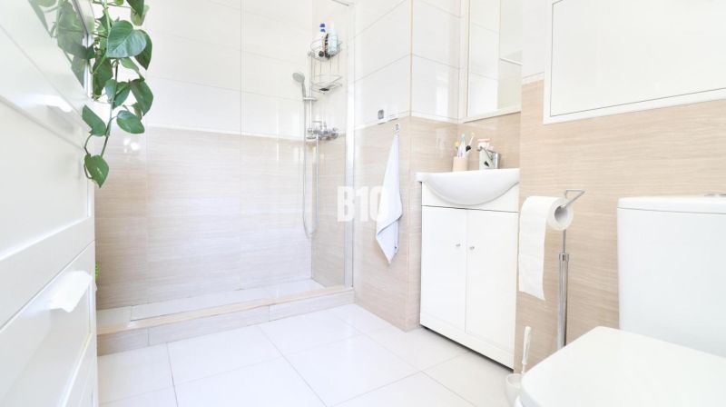 A bright bathroom with a shower and white cabinets in a 3-room apartment.