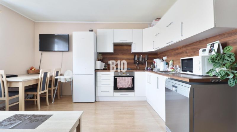 A kitchen in a 3-room apartment with white cabinets and a wooden decor floor.