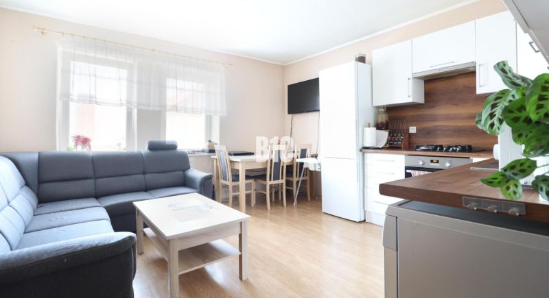 Living room in a three-room apartment with a wooden decor floor and light furniture.