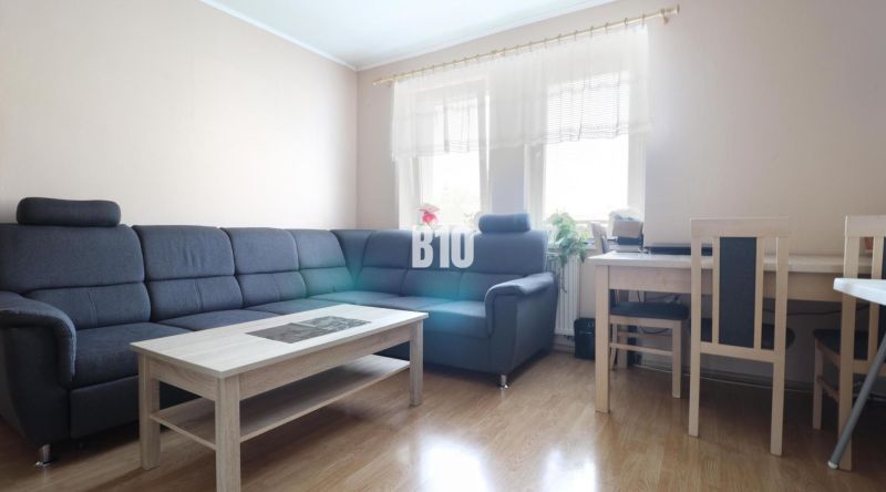 Living room in a 3-room apartment with a corner sofa and wooden floor decor.