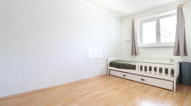 A bright room with a bed in a 3-room apartment, floor with wood decor.