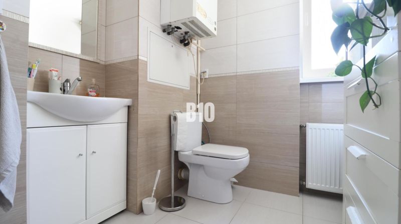 Bathroom with a sink and toilet in a 3-room apartment, light tiles and sanitary fixtures.