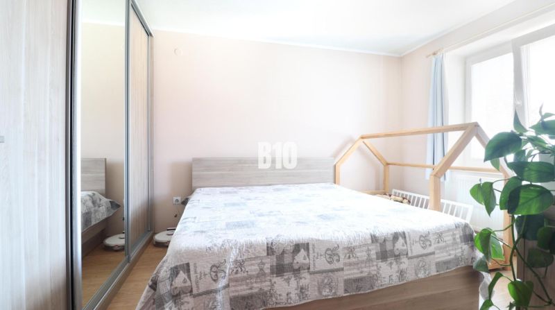 A bright bedroom in a 3-room apartment with a double bed and a wardrobe with a mirror.