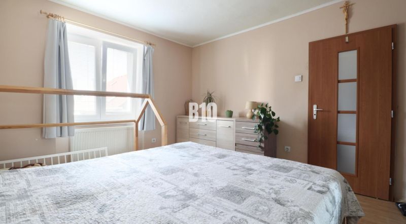 Bedroom in a 3-room apartment with a bed, dresser, and houseplants.