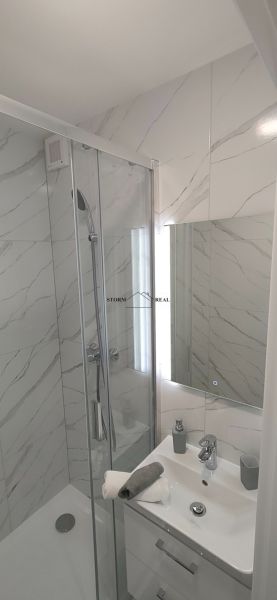 Bathroom with a shower and a sink in a 3-room apartment with marble-look tiles.