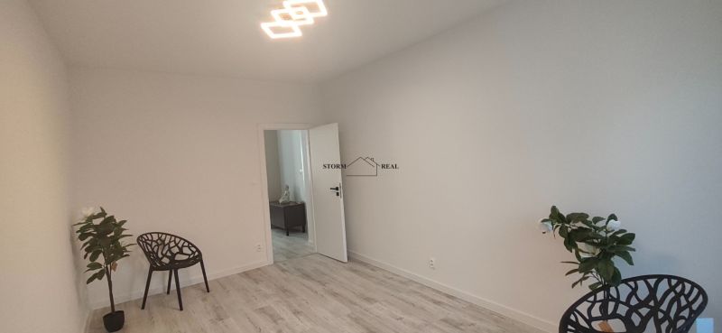 A room in a 3-room apartment with a wooden decor floor and a black chair.