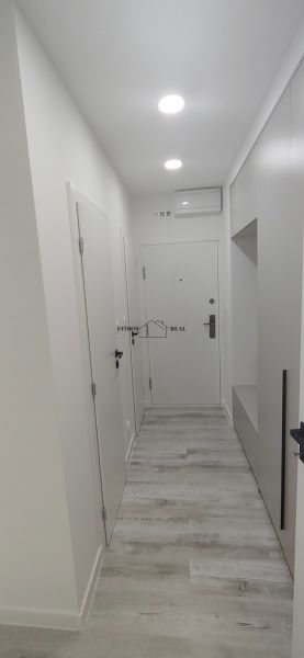 A hallway with white walls and a wooden decor floor in a 3-room apartment.