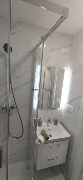 Bathroom in a 3-room apartment with a sink, mirror, and shower corner with a partition wall.