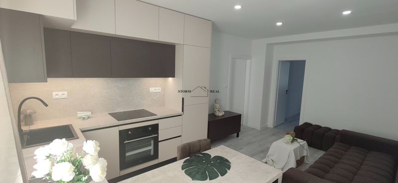 A kitchen with built-in appliances, a sofa, and a table in a 3-room apartment.