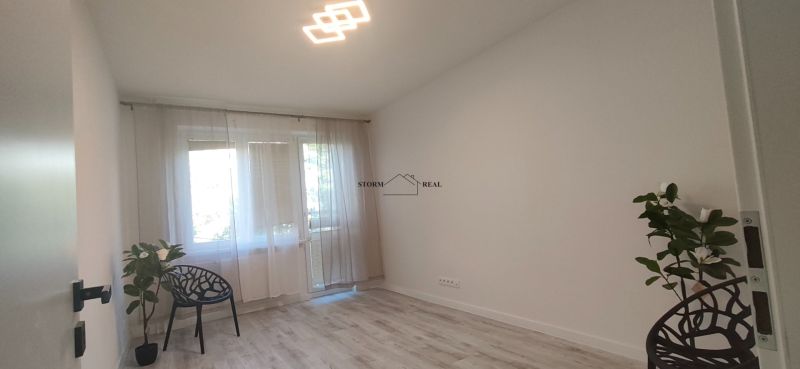 3-room apartment with wood-decor flooring, an armchair, and a potted plant.