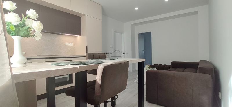 Kitchen and living room with a sofa in a three-room apartment, floor with wooden decor.