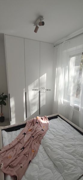 A bedroom with a large wardrobe in a 3-room apartment with white curtains.