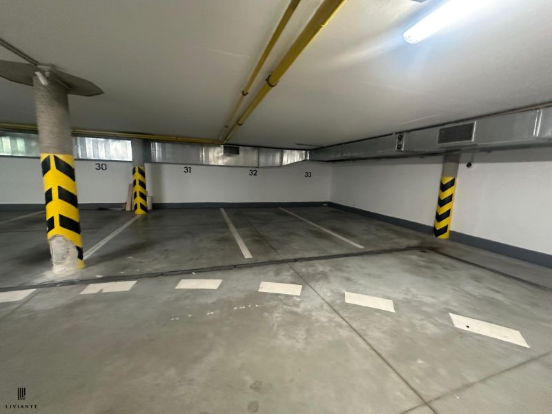 Underground parking lot with marked parking spaces and yellow-black column protection.