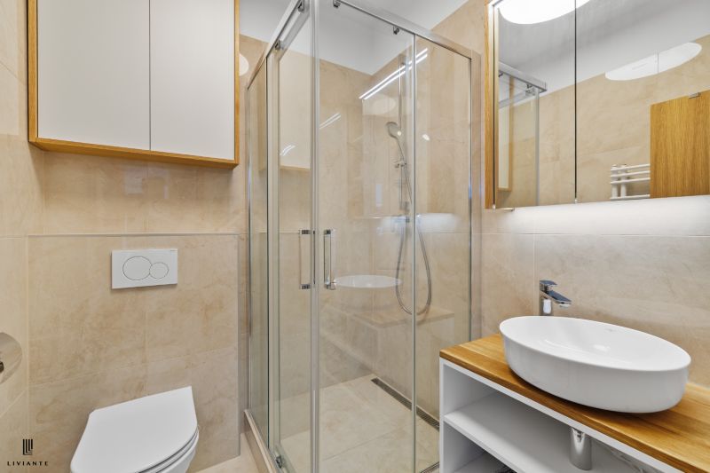 A bathroom with a glass shower enclosure and a sink in a 3-room apartment.