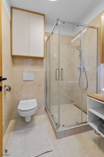 A bathroom with a shower and light tiles in a 3-room apartment.