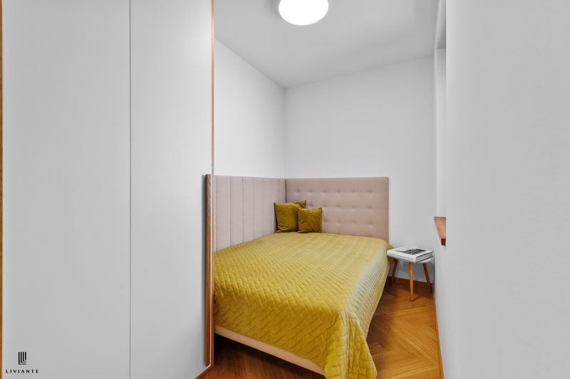 A bedroom with an upholstered headboard and a wooden decor floor in a 3-room apartment.