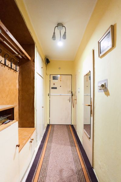 A hallway in a 3-room apartment with a coat rack, a mirror, and simple lighting.