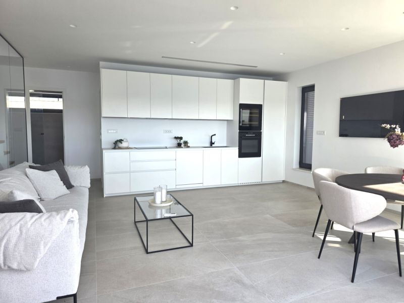 Open design in a 4-room apartment with a kitchen, living room, round table, and sofa.