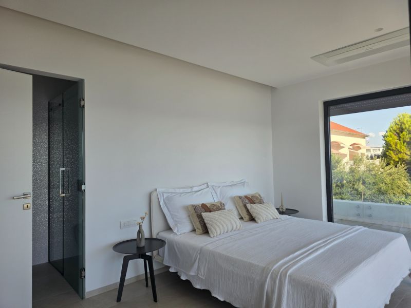 A bedroom in a 4-room apartment with a bed and a view of greenery through a large window.
