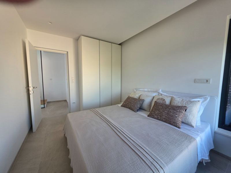 A bedroom with a gray bed, pillows, and a white wardrobe in a 4-room apartment.